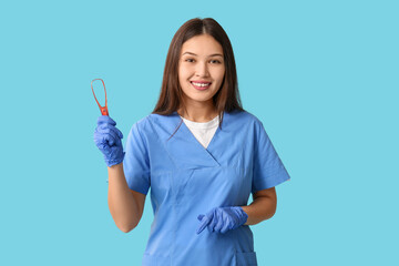 Young female dentist with tongue scraper on blue background