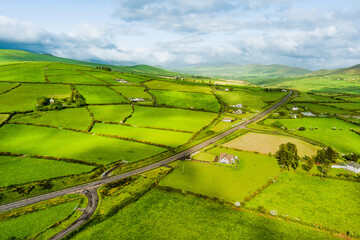 Aerial view of endless lush pastures and farmlands of Ireland's Dingle Peninsula. Irish countryside with emerald green fields and meadows. Rural landscape on sunset.
