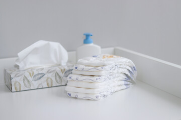 A stack of diapers and baby supplies on white changing table
