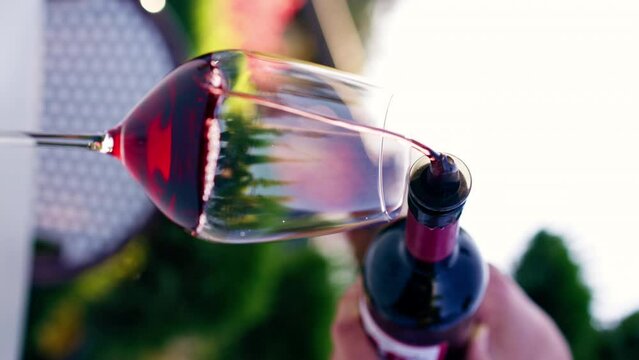 vertical video Close-up of a male sommelier's hand pouring aged wine from bottle into a glass for tasting on a vineyard
