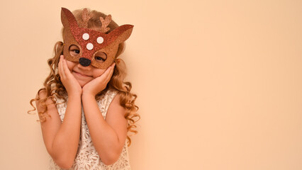 Unique child. Happy child in deer costume. Little cute girl in a carnival masquerade deer mask made of foamiran. The child is preparing to celebrate festival.
