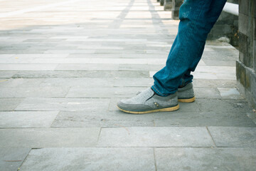 Man wearing sneakers and blue denim on paving block