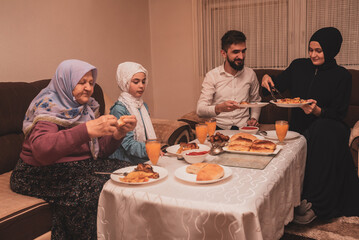 Happy Muslim family having iftar dinner during Ramadan dining table at home.