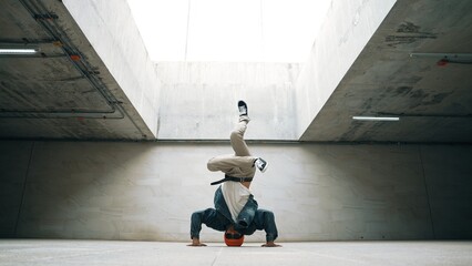 Stylish happy hipster perform break dance or freestyle foot step in building. Professional break...