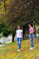 Obraz premium two adult female friends talking and walking in field full of yellow flowers during summer
