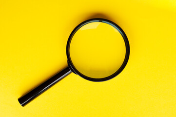 Top view of magnifying glass on yellow background with customizable space for text