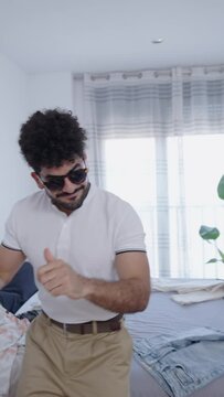 Bearded man with sunglasses dances in his room at home