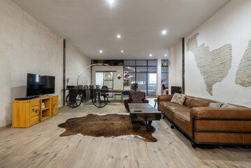 Large living room of a loft-type house with brown leather sofa, synthetic leather on the floor and...
