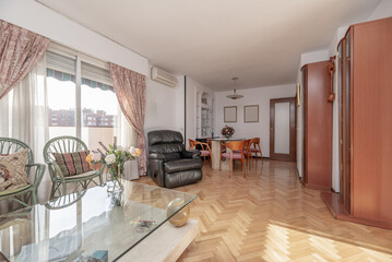 Living room of a conventional home with herringbone oak wood floors, terrace with aluminum window and terrace with terracotta floor