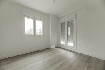 An empty room in a single-family house with a wall with access doors to a terrace with the blinds drawn