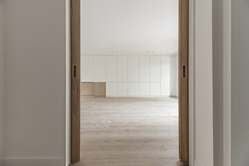 Open double sliding oak wooden doors that lead to a large empty living room