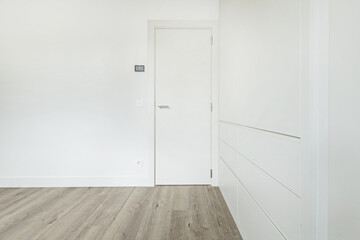 Empty room in a house with smooth walls and white wooden cabinets without handles