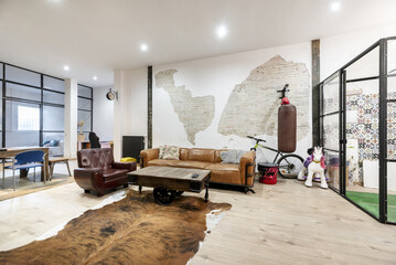 Living room of a loft home with brown leather sofa and industrial style furniture