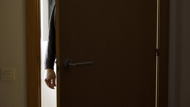 A dark room,a door opens with a silhouette of an unrecognisable man appears, he stands in the doorway and looks at his victim.Focus on shadow.