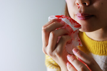 鼻血をティッシュ拭う女性