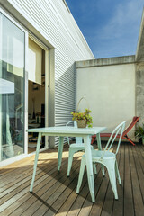 A pretty pastel blue metal garden table with matching chairs on an urban terrace with wooden floors