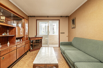 Small living room with antique shiny wooden furniture and a terrace with an aluminum enclosure in the background