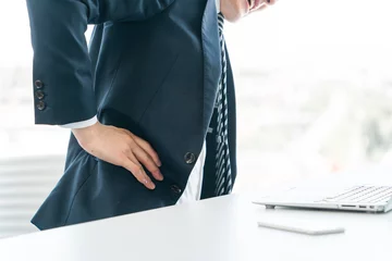 Fotobehang デスクワーク中に腰痛・脇腹痛で苦しむスーツ姿の男性ビジネスマン（ヘルニア・痺れ・疲労）  © buritora