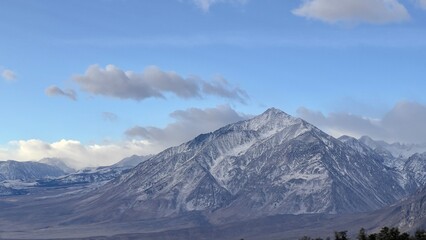 Snow-capped mountain with clouds overhead, seen from freeway near Bishop, California