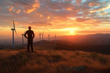 Tuinposter Engineer standing on the hill Windmills lined up and looking at the beautiful sunset landscape © panu101