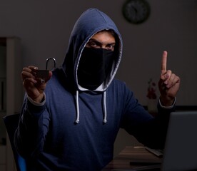 Male hacker hacking security firewall late in office