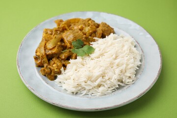 Delicious chicken curry with rice on green background, closeup