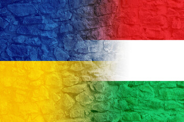 Flags of Ukraine and Hungary on stone wall. International diplomatic relationships
