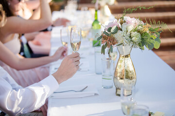 Close up of Guest Hands Holding Wine Glasses during Wedding Reception Toast or Speech with Gold Floral Centerpiece Decor on Table