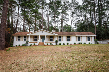 The front exterior entrance of a newly painted white siding brick ranch style house with a large...