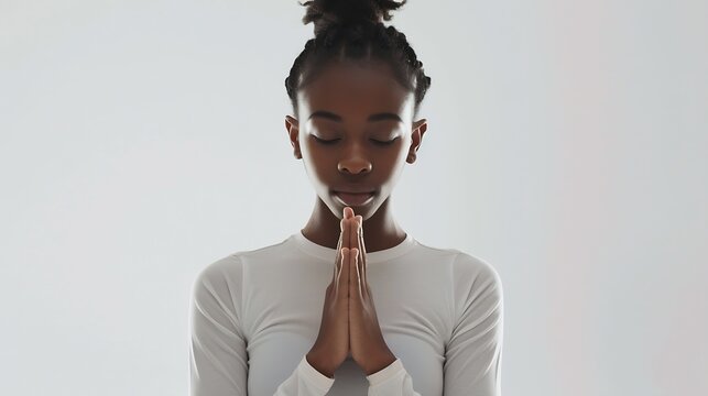 Meditation concept Beautiful young black woman stands in meditative pose enjoys peaceful atmosphere holds hands in praying gesture isolated over white background has sense of inner pea : Generative AI