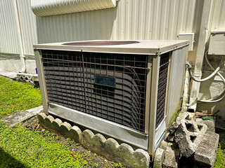 A residential outdoor air conditioning unit installed next to a mobile home, with clear weather...
