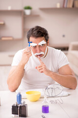 Young man shaving face at home