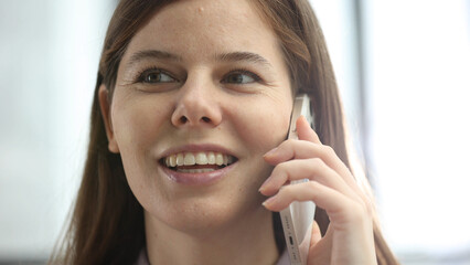 A woman's face is in close-up in the office, she is talking on the phone about a business decision