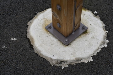 Wooden pole set in concrete and bolted in.