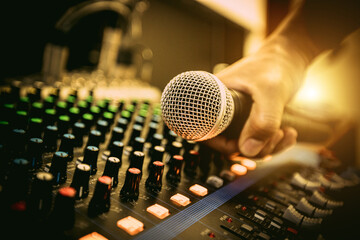 Hand sound engineer holding microphone on audio mixer in live broadcasting studio producer for...