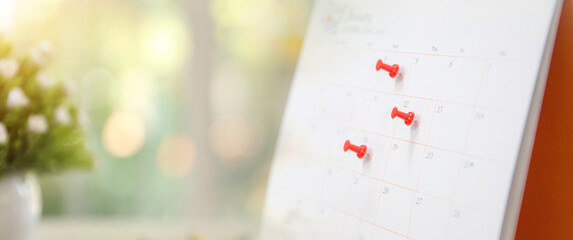 Red pin on blank desk calendar in office workplace concept time management event planner or...