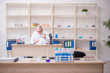 Old male chemist working at the lab