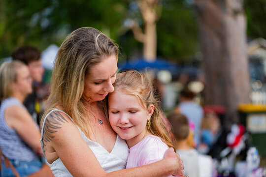 Portrait of a mother and daughter hugging together at community event