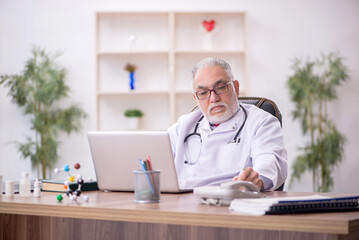 Old male doctor working in the clinic