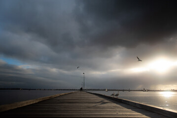 Como jetty with looming clouds at Perth, Western Australia. Moody, cloudy beautiful landscape scenery with flying seagull at the swan river