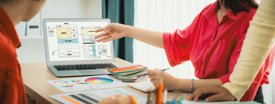 Cropped image of interior designer team discuss the material color while laptop displayed website wireframe designs for mobiles app and website. Creative design and business concept. Variegated.