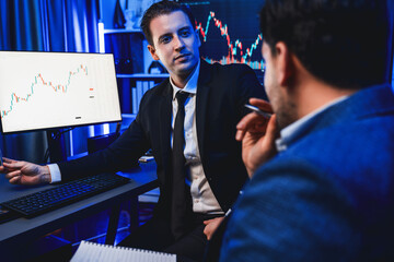 Two stock exchange traders discussing on dynamic investment graph, trending of high profit in...