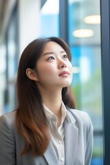 Businesswoman in Suit Looking Out Window of Skyscraper Office
