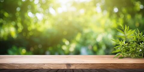 Fototapeta premium Sunlit wooden table with a green garden backdrop featuring grass, leaves, and blurred foliage.