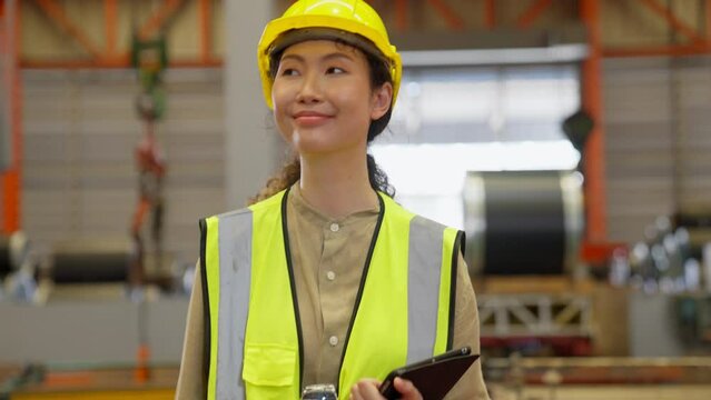 Asian Engineer or worker wear hard Hat working in a factory with heavy machinery. Industrial Specialist Standing in a Metal Construction Manufacturing. technicians and assistant workers in warehouse.