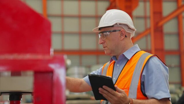 elderly man. Engineer or worker wear hard Hat working in factory with heavy machinery. Industrial Specialist Standing in Metal Construction Manufacturing. assistant technicians in warehouse.