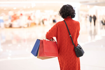 Fototapeta premium Back view of woman holding shopping bag