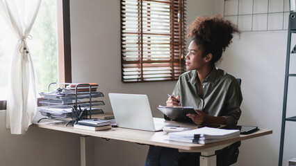 African american businesswoman looking outside window while writing notes and thinking new business