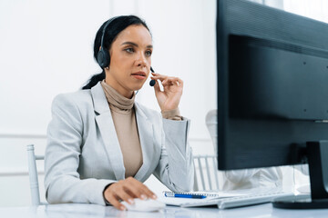 Fototapeta na wymiar African American businesswoman wearing headset working in office to support remote crucial customer or colleague. Call center, telemarketing, customer support agent provide service on video call.