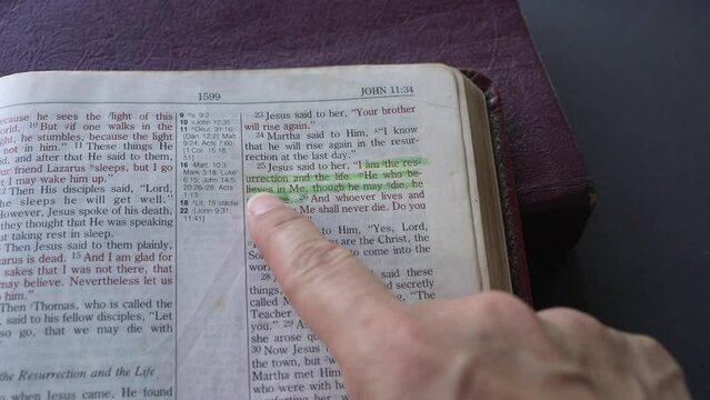 Finger pointing to highlighted bible scripture passage of John 11 and verse 25. Jesus is the resurrection and the life. A popular verse for Easter Day.
